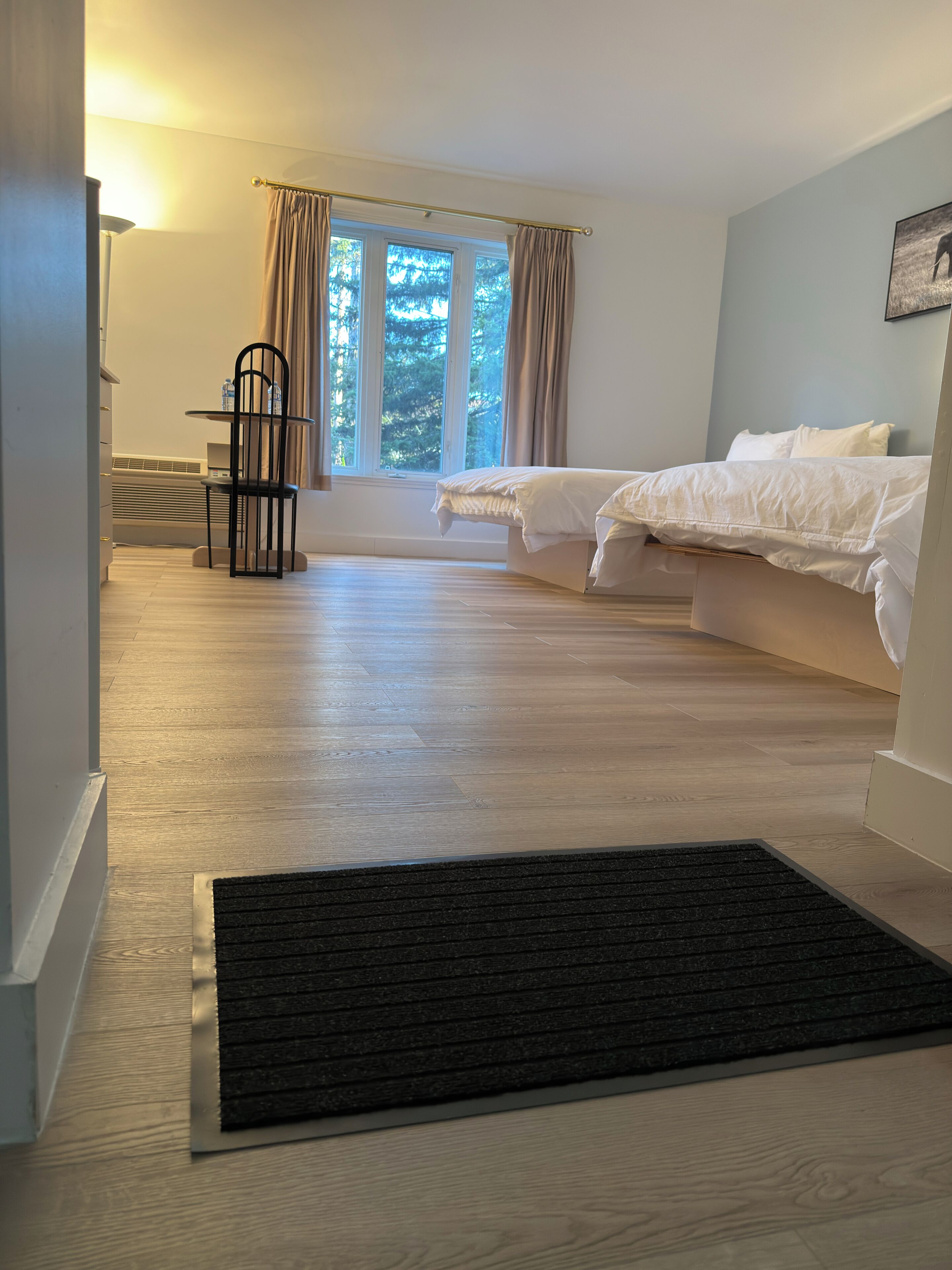 A bedroom with a bed, a chair, a desk, and a window with curtains.