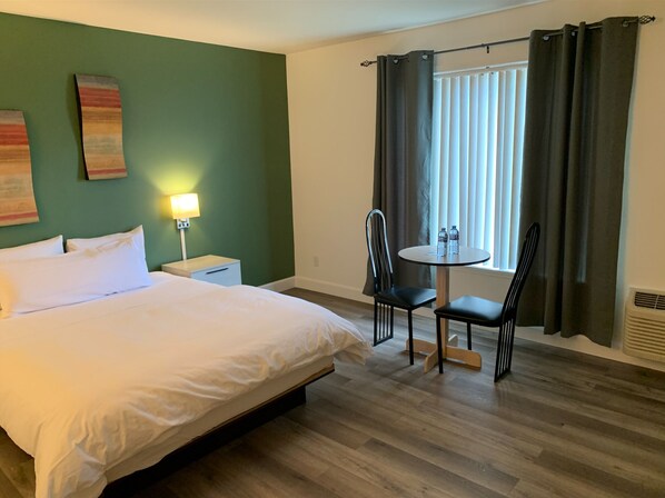 A hotel room with a bed, a nightstand, a table with chairs, and a window with curtains. - Hôtel saint-côme (Saint-Côme)