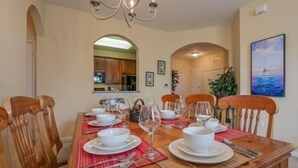 A dining area with a wooden table set for four, surrounded by wooden chairs. - Exclusive apartment at Vista Cay Resort (Orlando)