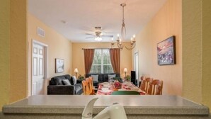 A kitchen with a modern faucet, a dining area with a table set for four, and a ceiling fan. - Exclusive apartment at Vista Cay Resort (Orlando)