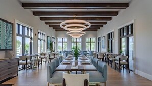 A spacious dining area with long tables and chairs, large windows, and a modern ceiling design. - Comfortable house for 8 guests at Solara Resort (Kissimmee)