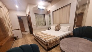 A bedroom with a bed, a round table, and two chairs. - The Aura Grand (Rohtak)