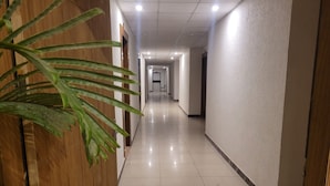 A long, well-lit hallway with tiled floors and wooden paneling on one side. - The Aura Grand (Rohtak)