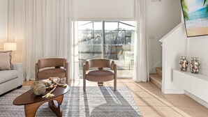 A living room with a sofa, two armchairs, a coffee table, and a large window with curtains. - Cozy 3BR house affordable at Bella Vida Resort (Kissimmee)