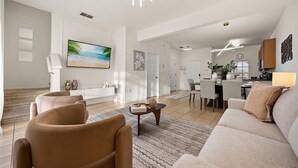A spacious living area with a large flat-screen TV, a sofa, and a dining area with chairs and a table. - Cozy 3BR house affordable at Bella Vida Resort (Kissimmee)