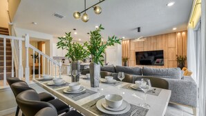 Uma área de jantar moderna com uma mesa comprida posta para quatro pessoas, rodeada por cadeiras pretas.