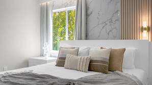 A modern bedroom with a large bed, a nightstand, a vase with flowers, and a window with curtains. - Comfortable 5BR Home Near Disney 10 min (Kissimmee)