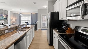 A modern kitchen with granite countertops, stainless steel appliances, and white cabinetry.