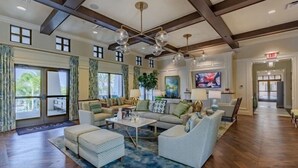 A spacious living room with a high ceiling, wooden beams, and a large chandelier. There are multiple seating areas with sofas and a coffee table. - Stylish 6BR Single Family at Solara Resort (Kissimmee)
