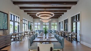 A spacious dining area with long tables and chairs, large windows, and a modern ceiling design. - Stylish 6BR Single Family at Solara Resort (Kissimmee)