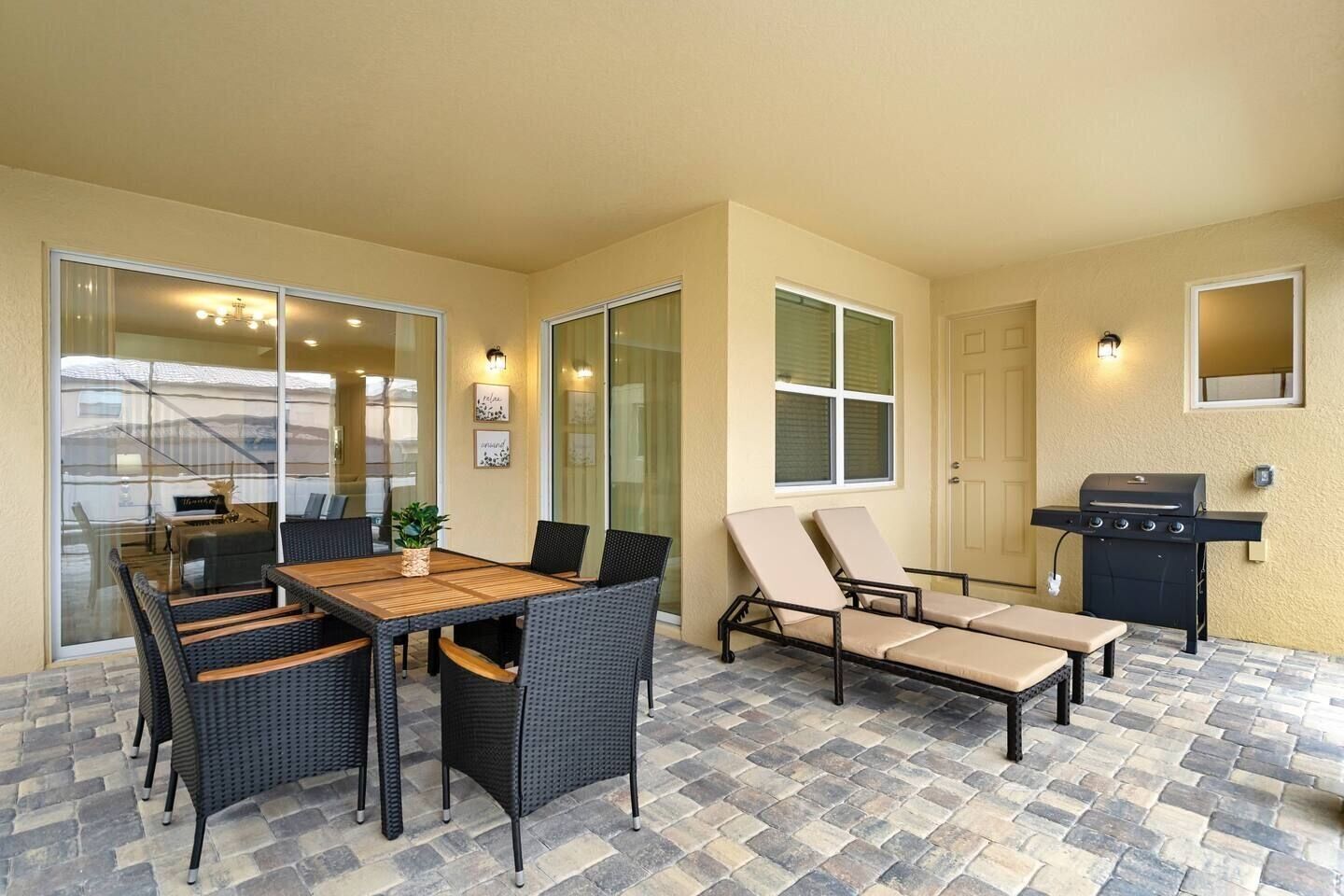 Une terrasse extérieure avec une table et des chaises pour les repas, un barbecue et des fauteuils de jardin.