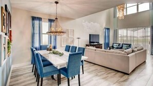 Un salon moderne avec un coin repas, comprenant un canapé, un téléviseur et un lustre.