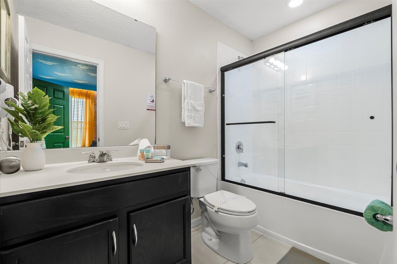 Casa de banho moderna com lavatório branco, toucador preto e cabine de duche em vidro.