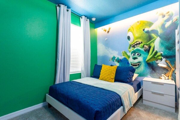 A bedroom with a bed, a nightstand, and a wall mural of animated characters.