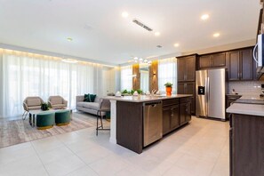A modern kitchen with a central island, stainless steel appliances, and dark wooden cabinets.