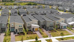 A residential area with modern, multi-story apartment buildings featuring a uniform architectural style, arranged in a grid pattern with well-maintained lawns and driveways.