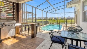A covered patio area with a grill, pool, and outdoor seating.