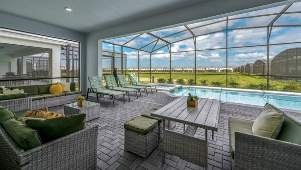 A covered outdoor area with wicker furniture, a pool, and a view of the landscape.