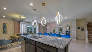 A modern kitchen with granite countertops, dark cabinetry, and pendant lighting.