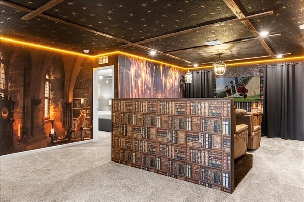 A room with a bookshelf, a wooden desk, a television, and a chair.