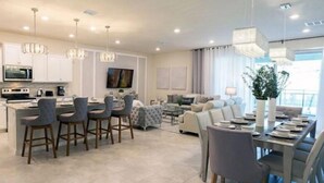 Una cocina moderna con una isla central, taburetes de bar y un comedor con mesa para cuatro.