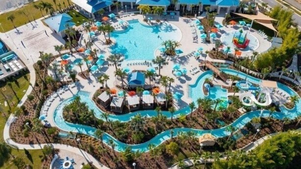 An aerial view of a resort with a large central pool, multiple water slides, and sun loungers.
