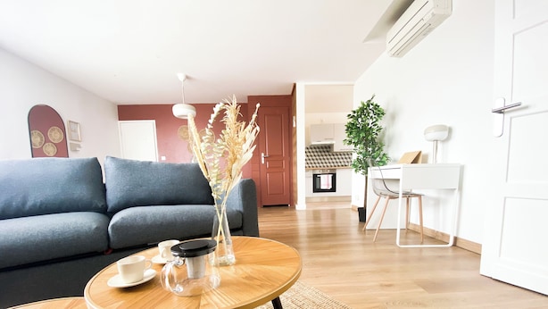 Un salon avec un canapé, une table basse et un vase contenant des plantes séchées.