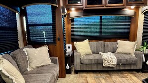 Interni accoglienti di un camper con divani a righe, pavimento in legno e ampie finestre.