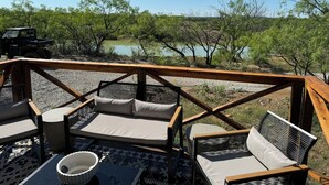 Una terrazza con posti a sedere all'aperto, vista su un lago e un veicolo nelle vicinanze.
