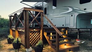 Un camper con veranda in legno e piante in vaso.