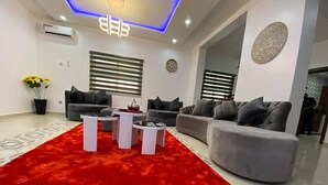 Een moderne woonkamer met een rood tapijt, grijze banken en een witte salontafel.
