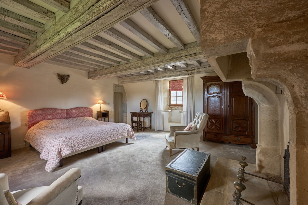 Une chambre à coucher avec un grand lit, une chaise, une armoire en bois et une petite table.