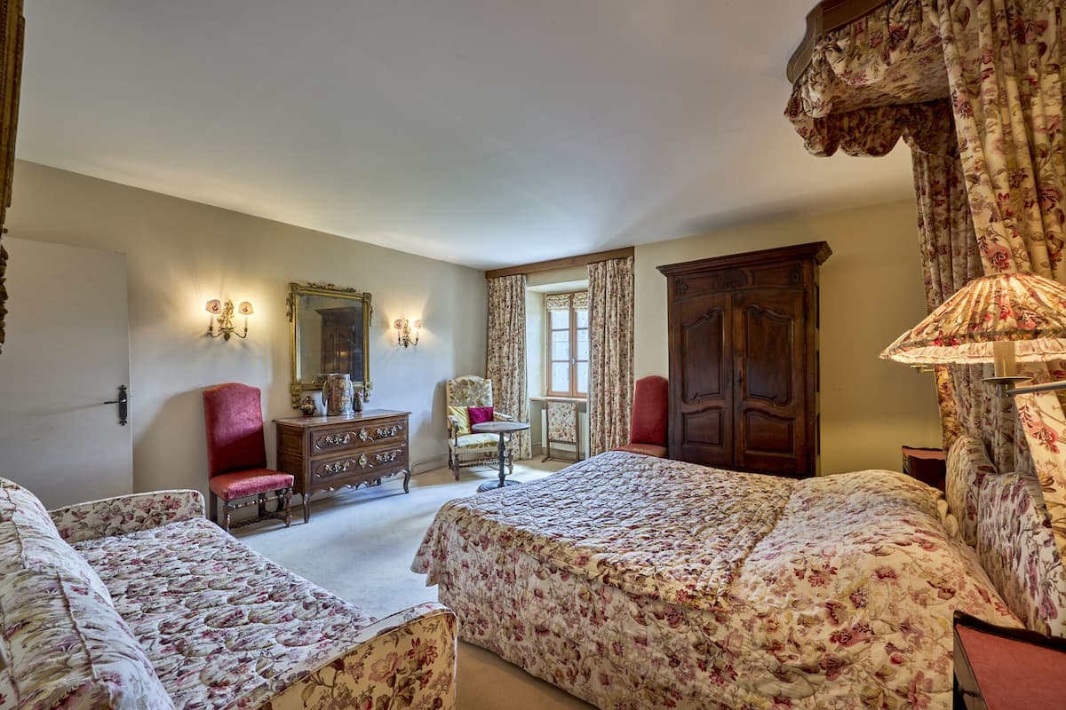 Une chambre avec deux lits, une commode, un miroir et une fenêtre avec des rideaux.