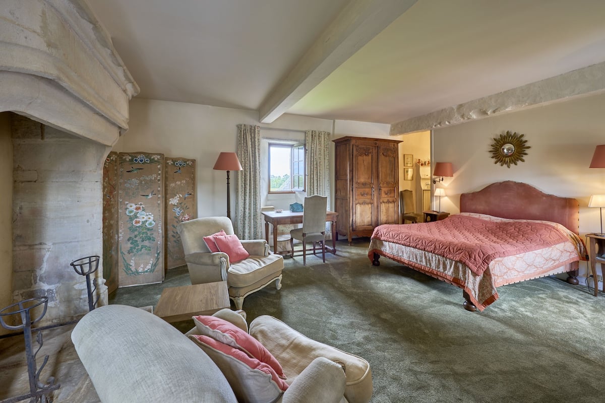 Une chambre à coucher avec un grand lit, une chaise, une petite table et une armoire.