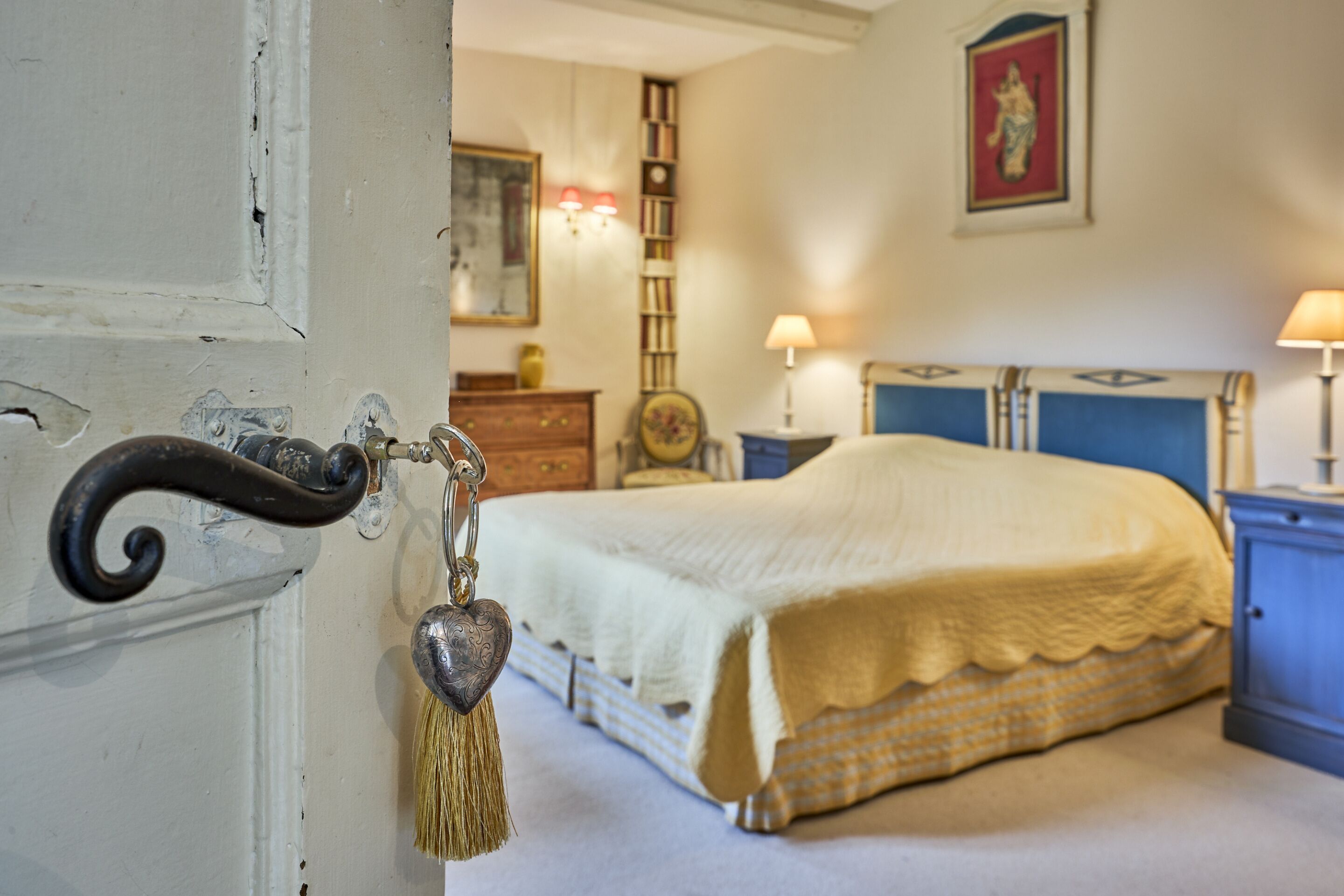 Un dormitorio con cama, mesita de noche, cómoda y puerta con llave.