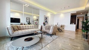 A modern living room with a sectional sofa, a round coffee table, and a dining area with a small table and chairs.