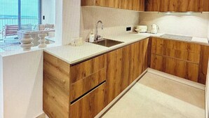 A modern kitchen with wooden cabinetry, a large island with a sink, and a view of the outdoors.