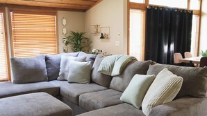 A living room with a sectional sofa, a dining table, and a potted plant. - Superhome Riverbottoms Home in Bismarck (Bismarck)