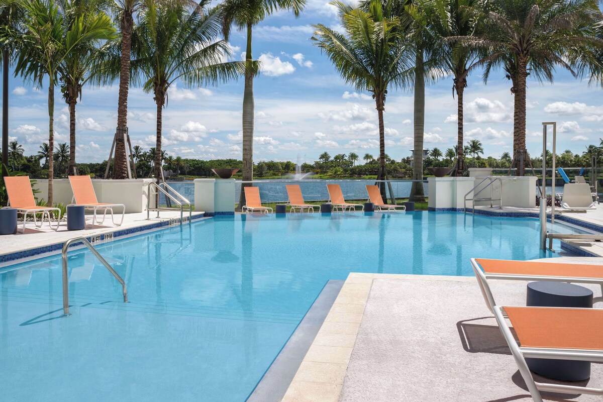 A swimming pool with lounge chairs and palm trees.