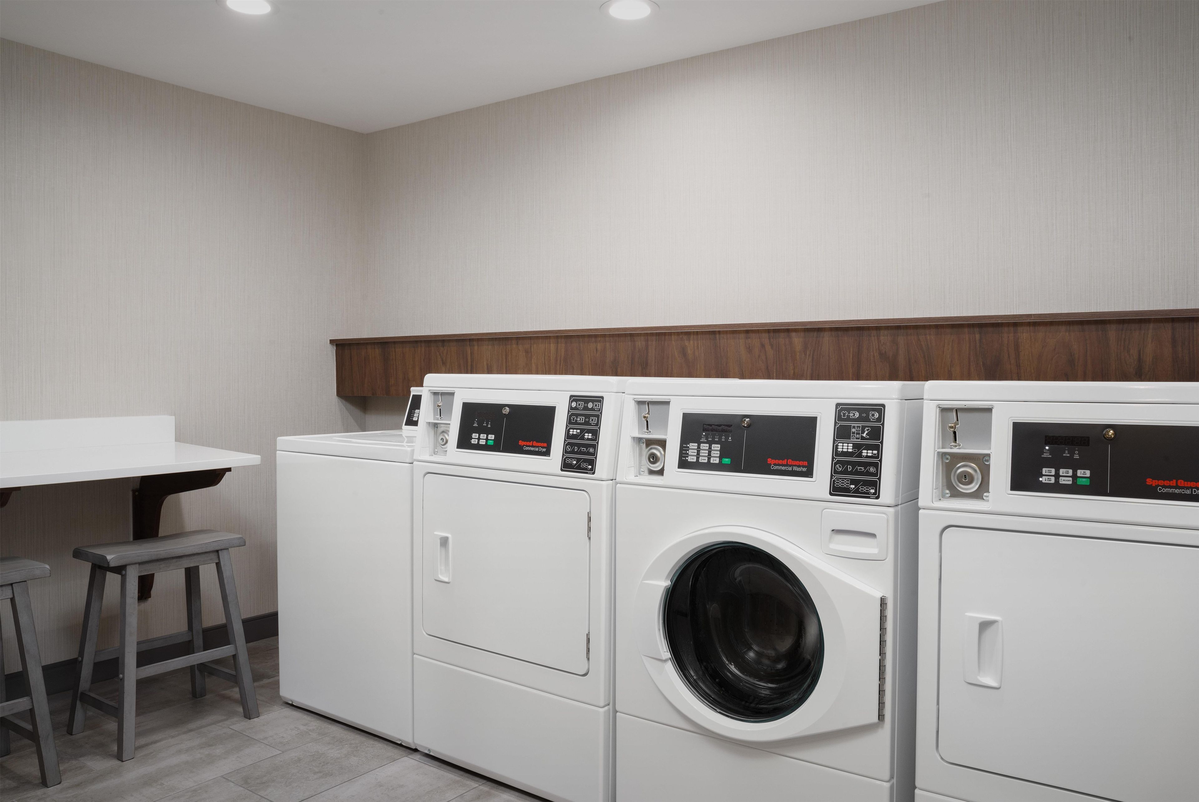 A laundry room with a white washing machine, a dryer, and a bench.