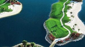 A golf course with a winding path, sand bunkers, and palm trees. - Hampton Inn & Suites Naples South (Naples)