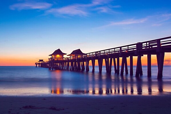 A pier extending into the water with two structures at the end, likely accommodations, during sunset. - Hampton Inn & Suites Naples South (Naples)