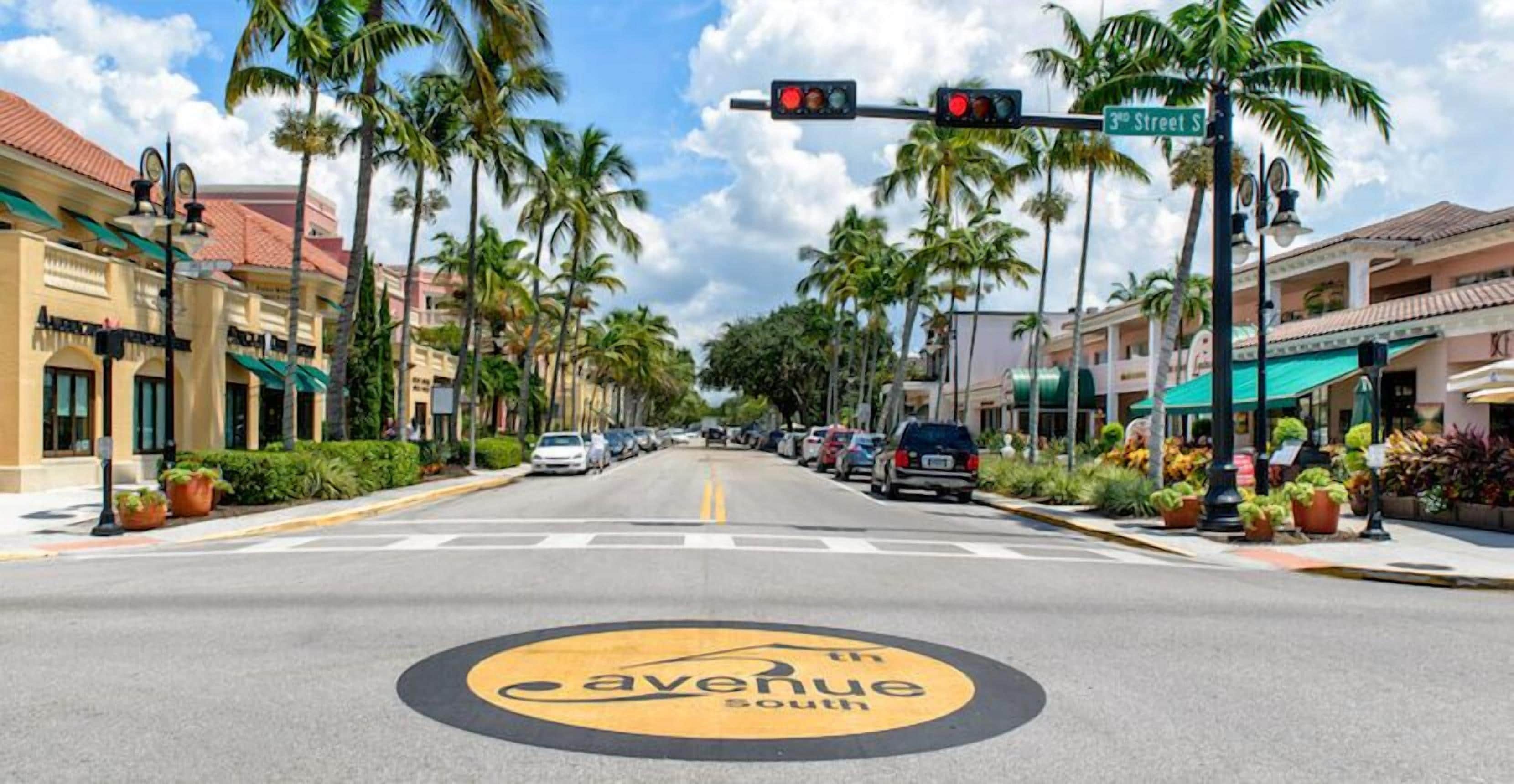 Un carrer amb un senyal que diu '3rd Street', palmeres i una indicació de carretera que marca '5th Avenue South'.