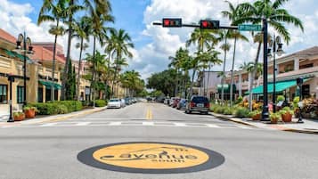 Un carrer amb un senyal que diu '3rd Street', palmeres i una indicació de carretera que marca '5th Avenue South'.