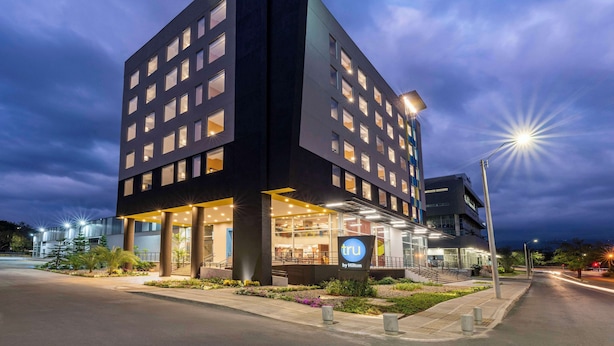A modern hotel with a prominent corner entrance, large windows, and a well-lit facade. - Tru By Hilton Cali Sur (Cali)
