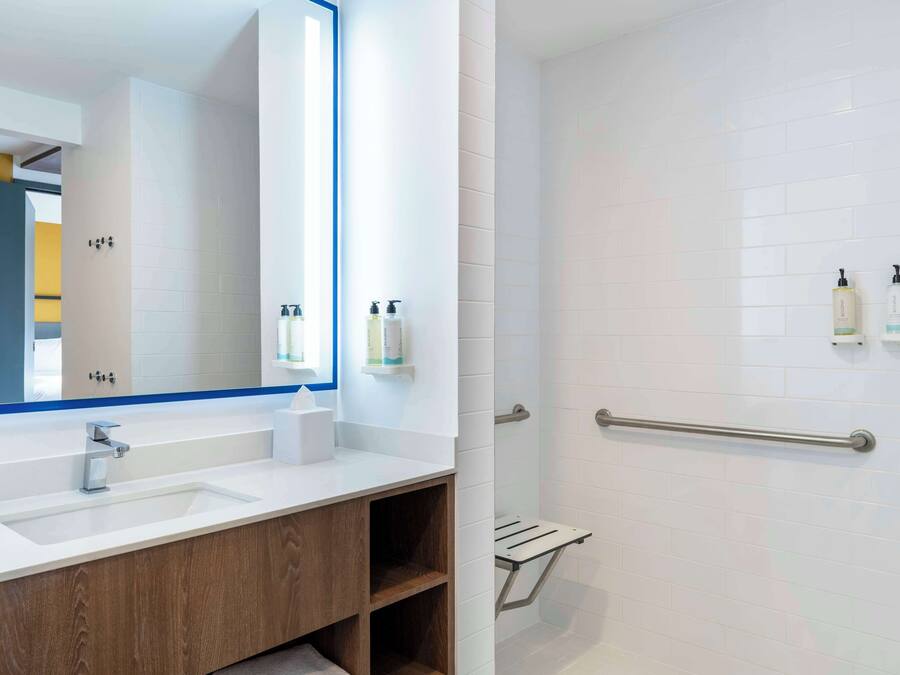 A modern bathroom with a white sink, wooden vanity, and a glass shower enclosure.