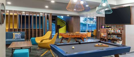 A modern lounge area with a pool table, seating, and a foosball table.