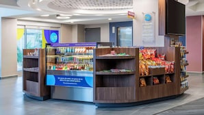 A snack kiosk with a variety of snacks and beverages, a digital screen displaying information, and a sign with the logo 'tru'. - Tru By Hilton Cali Sur (Cali)