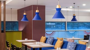A modern restaurant with blue pendant lights, wooden chairs, and tables with white placemats. - Tru By Hilton Cali Sur (Cali)