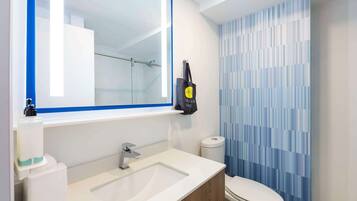 A modern bathroom with a large mirror, a sink, and a toilet.